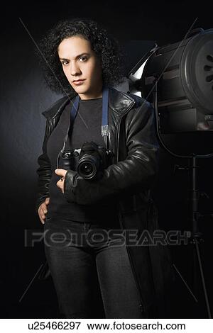 Stock Photo - Woman holding digital camera in studio setting.. Fotosearch
