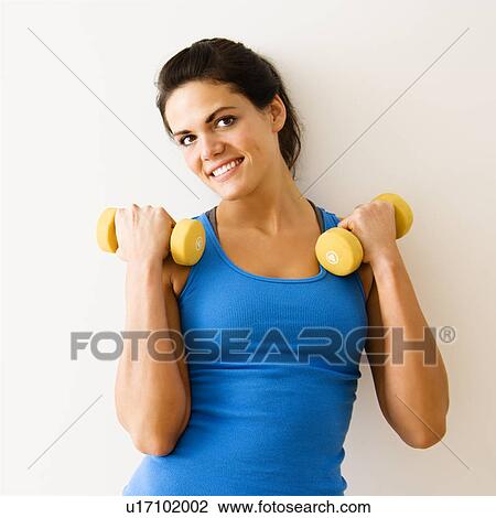 Stock Image - Woman holding hand weights and smiling.. Fotosearch