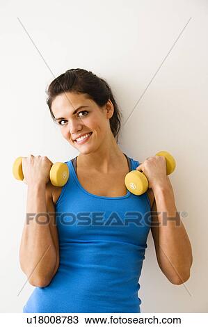 Woman holding hand weights and smiling View Large Photo Image Stock Image - Woman holding hand weights and smiling. Fotosearch