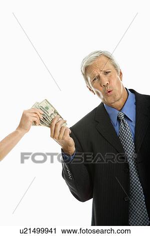 Stock Image - Woman holding money with businessman making facial expression. Fotosearch