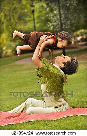Woman holding toddler up in air and smiling in park. View Large Photo Image Picture - Woman holding toddler up in air and smiling in park.. Fotosearch