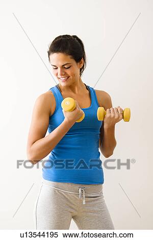 Stock Photography - Woman lifting hand weights and smiling. Fotosearch