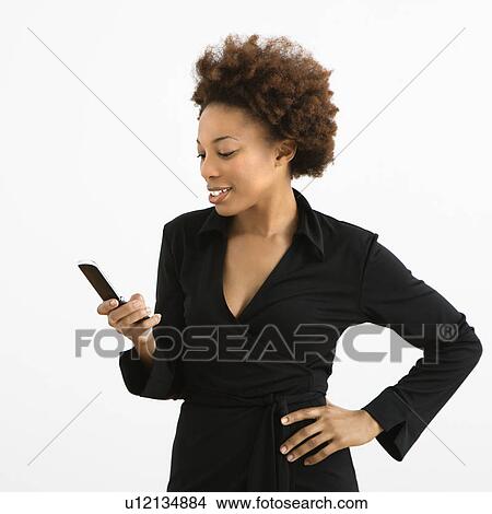 Picture - Woman looking at cellphone standing . Fotosearch