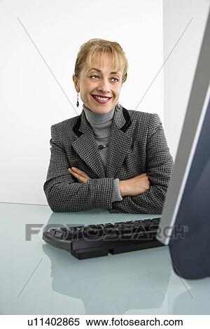 Woman looking at computer and smiling with arms crossed View Large Photo Image Stock Photography - Woman looking at computer and smiling with arms crossed. Fotosearch