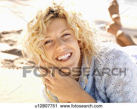 Stock Image - Woman lying in sand on Maui, Hawaii beach smiling.. Fotosearch