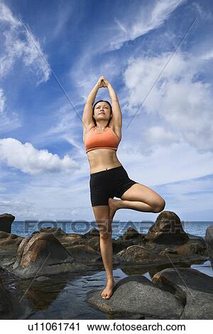 Woman on rock by ocean in Maui, Hawaii doing standing tree yoga pose View Large Photo Image Stock Image - Woman on rock by ocean in Maui, Hawaii doing standing tree yoga pose. Fotosearch