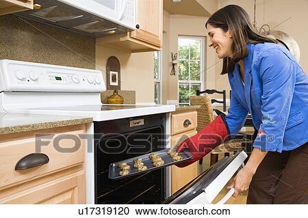 Woman putting cookies into oven View Large Photo Image Stock Image - Woman putting cookies into oven. Fotosearch