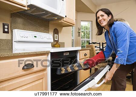 Woman putting cookies into oven View Large Photo Image Stock Photo - Woman putting cookies into oven. Fotosearch