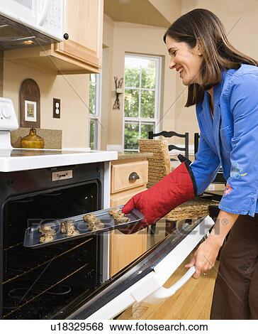 Woman putting cookies into oven View Large Photo Image Stock Photo - Woman putting cookies into oven. Fotosearch