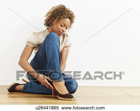 Woman putting on high heel shoes sitting on wood floor. View Large Photo Image Stock Photography - Woman putting on high heel shoes sitting on wood floor.. Fotosearch