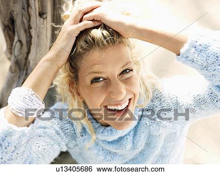 Woman sitting on beach in smiling and holding back hair with hands View Large Photo Image Stock Photograph - Woman sitting on beach in smiling and holding back hair with hands. Fotosearch