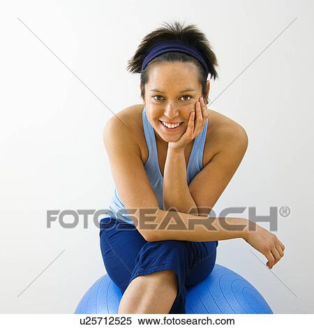 Stock Photography - Woman sitting on fitness balance ball smiling. Fotosearch