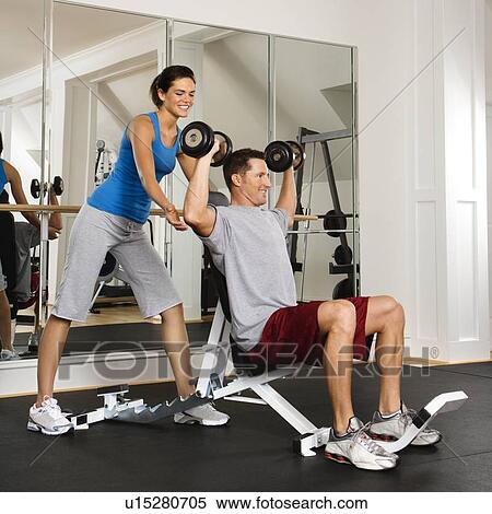 Woman spotting man lifting weights at gym View Large Photo Image Stock Photography - Woman spotting man lifting weights at gym. Fotosearch