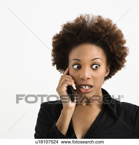 Woman talking on cellphone looking shocked against white background. View Large Photo Image Picture - Woman talking on cellphone looking shocked against white background.. Fotosearch