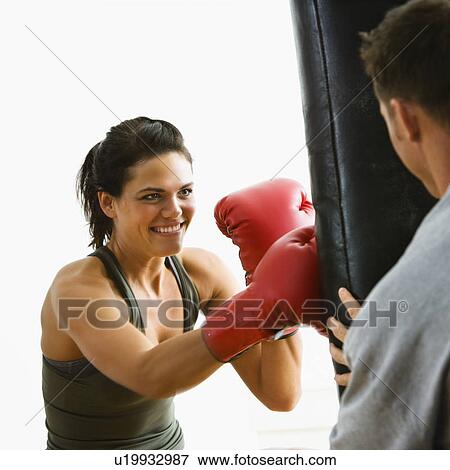 Stock Photo - Woman wearing boxing gloves hitting training mitts man is holding. Fotosearch