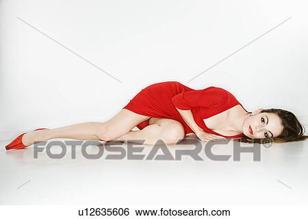 Stock Photograph - Woman wearing red dress lying on floor. Fotosearch