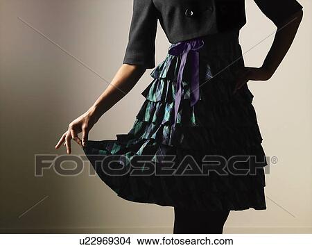 Picture - Woman wearing ruffled dress holding it out gracefully with fingers. Fotosearch