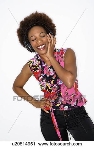 Woman with afro wearing vintage print fabric and listening to headphones smiling. View Large Photo Image Stock Image - Woman with afro wearing vintage print fabric and listening to headphones smiling.. Fotosearch
