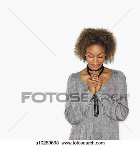 Stock Photo - Woman with hands clasped together in prayer and eyes closed. Fotosearch