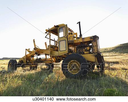 Stock Image - Yellow tractor in field. . Fotosearch