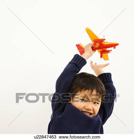 Stock Image - Young boy playing with plastic toy airplane. Fotosearch