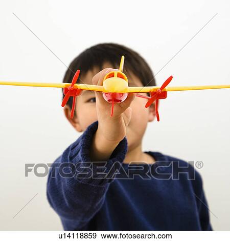 Stock Photo - Young boy playing with plastic toy airplane. Fotosearch