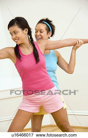 Young woman helping another young woman with positioning on her yoga pose View Large Photo Image Stock Photo - Young woman helping another young woman with positioning on her yoga pose. Fotosearch
