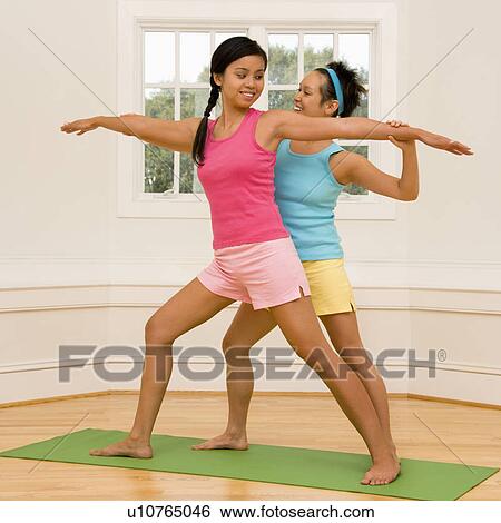 Young woman helping another young woman with positioning on her yoga pose. View Large Photo Image Stock Photograph - Young woman helping another young woman with positioning on her yoga pose.. Fotosearch