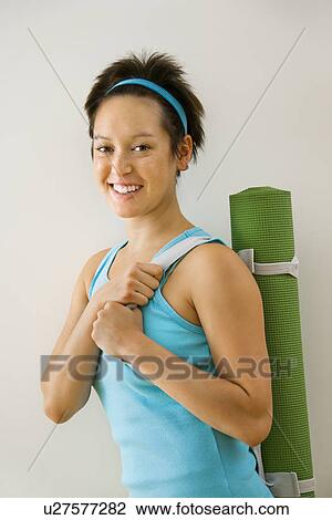 Young woman holding exercise mat and smiling. View Large Photo Image Stock Image - Young woman holding exercise mat and smiling.. Fotosearch