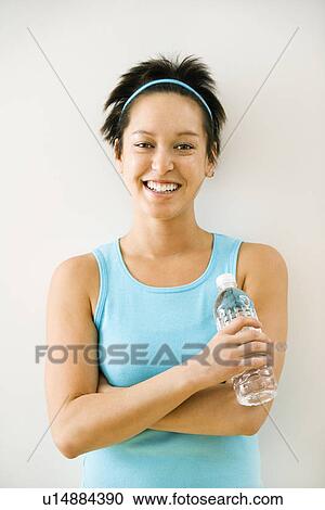 Young woman in exercise clothes holding bottle of water smiling. View Large Photo Image Stock Image - Young woman in exercise clothes holding bottle of water smiling.. Fotosearch