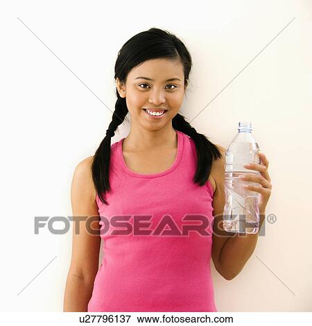 Young woman in fitness outfit holding bottled water and smiling. View Large Photo Image Stock Photo - Young woman in fitness outfit holding bottled water and smiling.. Fotosearch