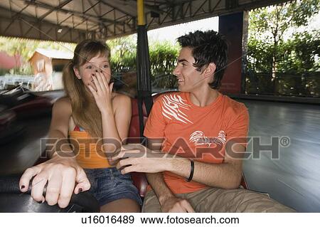 Stock Photo - Teenage couple in bumper car in amusement park. Fotosearch