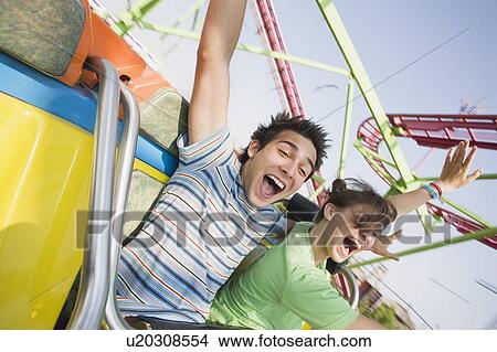 Picture - Teenage couple on amusement park ride. Fotosearch