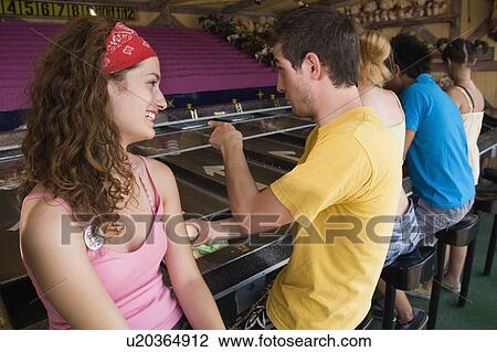 Teenage couple playing game in amusement park View Large Photo Image Stock Image - Teenage couple playing game in amusement park. Fotosearch