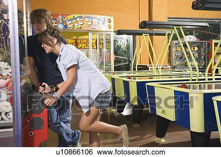 Stock Photograph - Teenagers playing game in arcade. Fotosearch