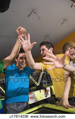 Stock Photograph - Teenagers playing game in arcade. Fotosearch