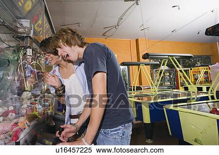 Stock Photography - Teenagers playing game in arcade. Fotosearch
