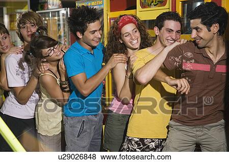 Stock Photo - Teenagers pushing on line in arcade. Fotosearch
