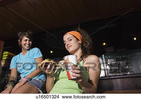 Two female teenagers hanging out, eating pizza View Large Photo Image Picture - Two female teenagers hanging out, eating pizza. Fotosearch