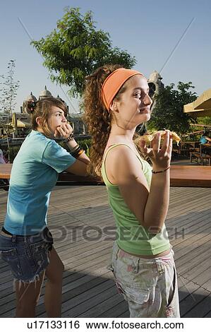 Stock Photograph - Two female teenagers hanging out, eating pizza. Fotosearch