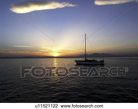 Stock Image - A lonely sail boat enjoying the peace of the setting sun. Red Sea. Egypt. Fotosearch