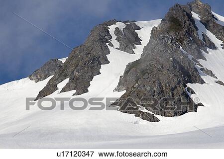 Stock Photo - View of the snow-covered cliffs in sunlight surrounding Takatz Bay on Baranof Island, Southeast Alaska, USA. Pacific Ocean.. Fotosearch