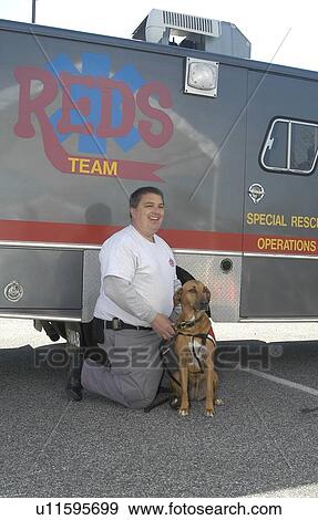 Stock Photo - Man with service dog in front of Rescue Team truck. Fotosearch