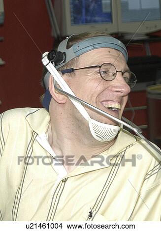 Picture - Man with significant disabilities utilizing headgear to operate communications apparatus.. Fotosearch