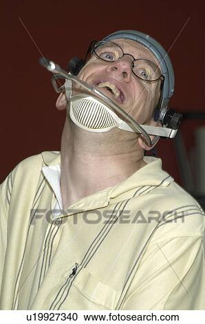 Stock Image - Man with significant disabilities utilizing headgear to operate communications apparatus.. Fotosearch