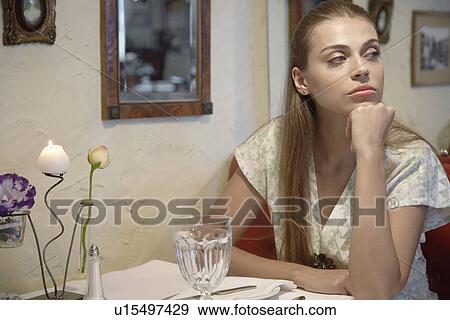 Stock Photo - Bored woman sitting at dining table. Fotosearch