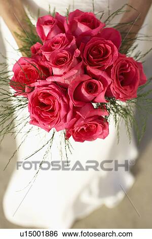Stock Photograph - Bride holding bouquet (focus on flowers). Fotosearch