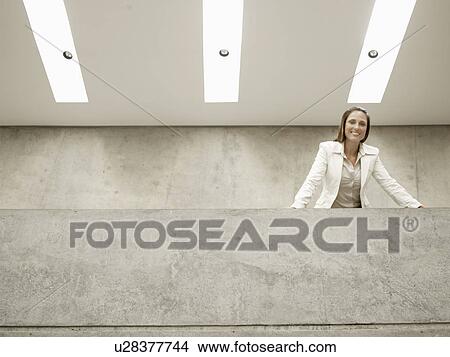 Picture - Businesswoman leaning against wall (portrait, low angle view). Fotosearch