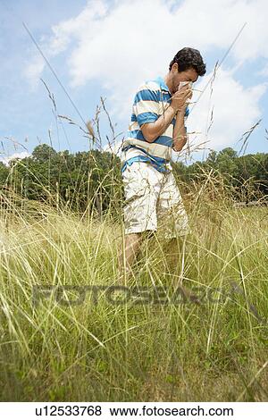 Stock Photo - Man blowing nose in field (low angle view). Fotosearch