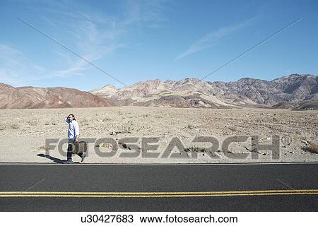Man with suitcase walking on highway View Large Photo Image Stock Image - Man with suitcase walking on highway. Fotosearch